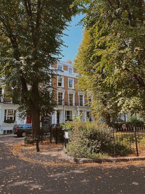 A row of colourful Victorian terraced houses on Phillimore Gardens in Kensington, featuring pastel pink, blue, yellow, and white facades with sash windows and decorative mouldings. In the foreground, 