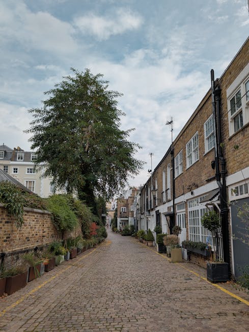 A multi-storey residential building with a brick and cream façade, featuring curved bay windows with black wrought iron railings, classical architectural details such as columns and balustrades, and 